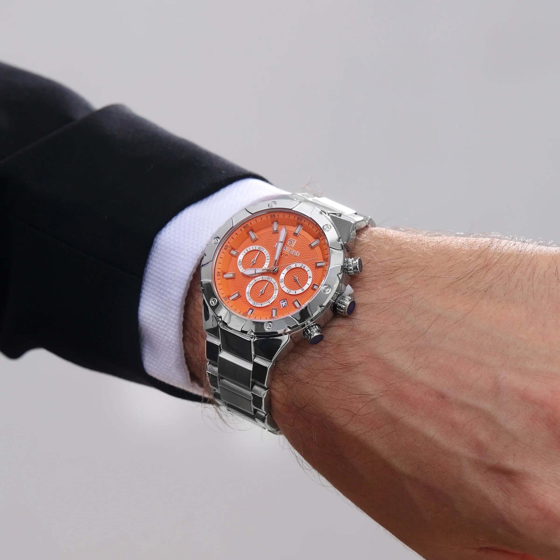 Homem usando relógio masculino REWARD VIP Legacy com mostrador laranja e pulseira de aço inoxidável, combinando com traje social.