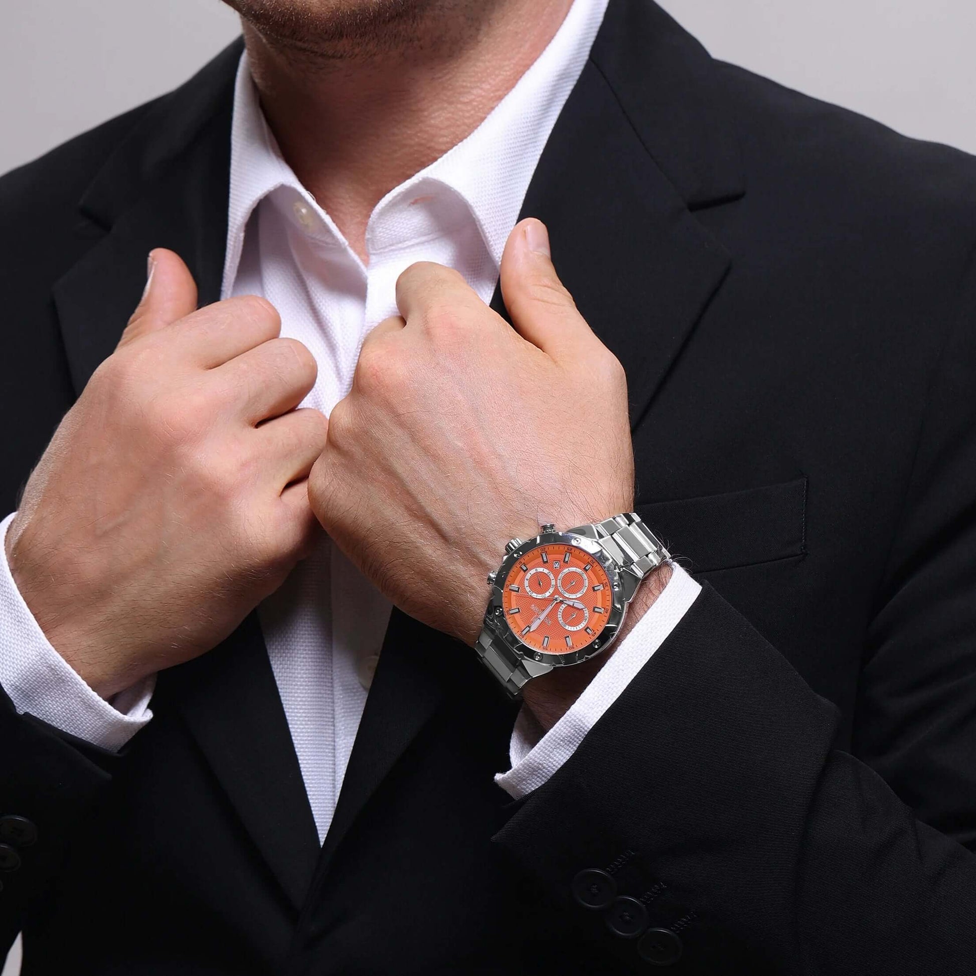 Homem usando relógio masculino REWARD VIP Legacy com mostrador laranja e pulseira de aço inoxidável, combinando com traje social.